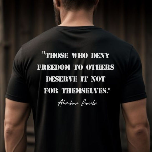 Young man with beard and short hair wearing a black Abraham Lincoln patriotic shirt that says those who deny freedom to others deserve it not for themselves created by graphic apparel shop Midnight Gypsy Designs as part of their patriotic apparel clothing line. Perfect USA patriotic tee, USA patriotic t-shirt, USA veterans shirt, We the People Shirt, USA Military Shirt, US Constitution Shirt, fourth of July shirt, patriotic pride shirt, USA veterans shirt, and Abraham Lincoln shirt.