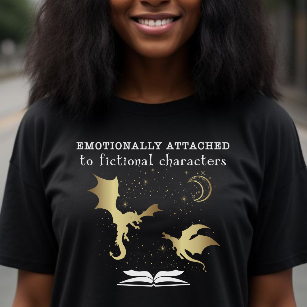 Young woman with shoulder length hair wearing a black Emotionally Attached to Fictional Characters shirt with two gold dragons flying over an open book and a crescent moon created by graphic apparel company Midnight Gypsy Designs for their academia book merch collection. Perfect fantasy readers shirt, book dragon shirt, fourth wing shirt, book merch, bookish merch, and shirt for fantasy readers.