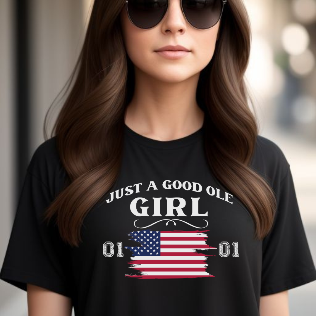 Young woman with long brown hair in sunglasses wearing a black Just A Good Ole Girl shirt with American flag and General Lee 01 number created by graphic apparel company Midnight Gypsy Designs as part of their Patriotic Pride Apparel Collection. Perfect Dukes of Hazard shirt, Dukes of Hazard t-shirt, Daisy Duke shirt, Daisy Duke t-shirt, General Lee shirt, General Lee t-shirt, and USA Patriotic shirt.