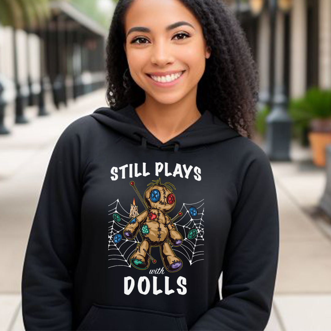 Young woman with long dark hair in New Orleans Bourbon Street wearing a black Still Plays With Dolls Voodoo hoodie with Voodoo doll on front designed by graphic apparel company Midnight Gypsy Designs.