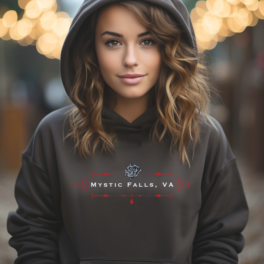 Young woman with wavy brown hair wearing a black Mystic Falls hoodie that says Look Like a Salvatore, Act Like a Forbes, and Love Like a Gilbert with black rose and red blood drip created by graphic apparel company Midnight Gypsy Designs as part of their The Vampire Diaries apparel line. Perfect Vampire Diaries hoodie, Stefan Salvatore hoodie, Damon Salvatore hoodie, Mystic Falls shirt, Bonnie Bennett shirt, Caroline Forbes shirt, and Salvatore Brothers hoodie.