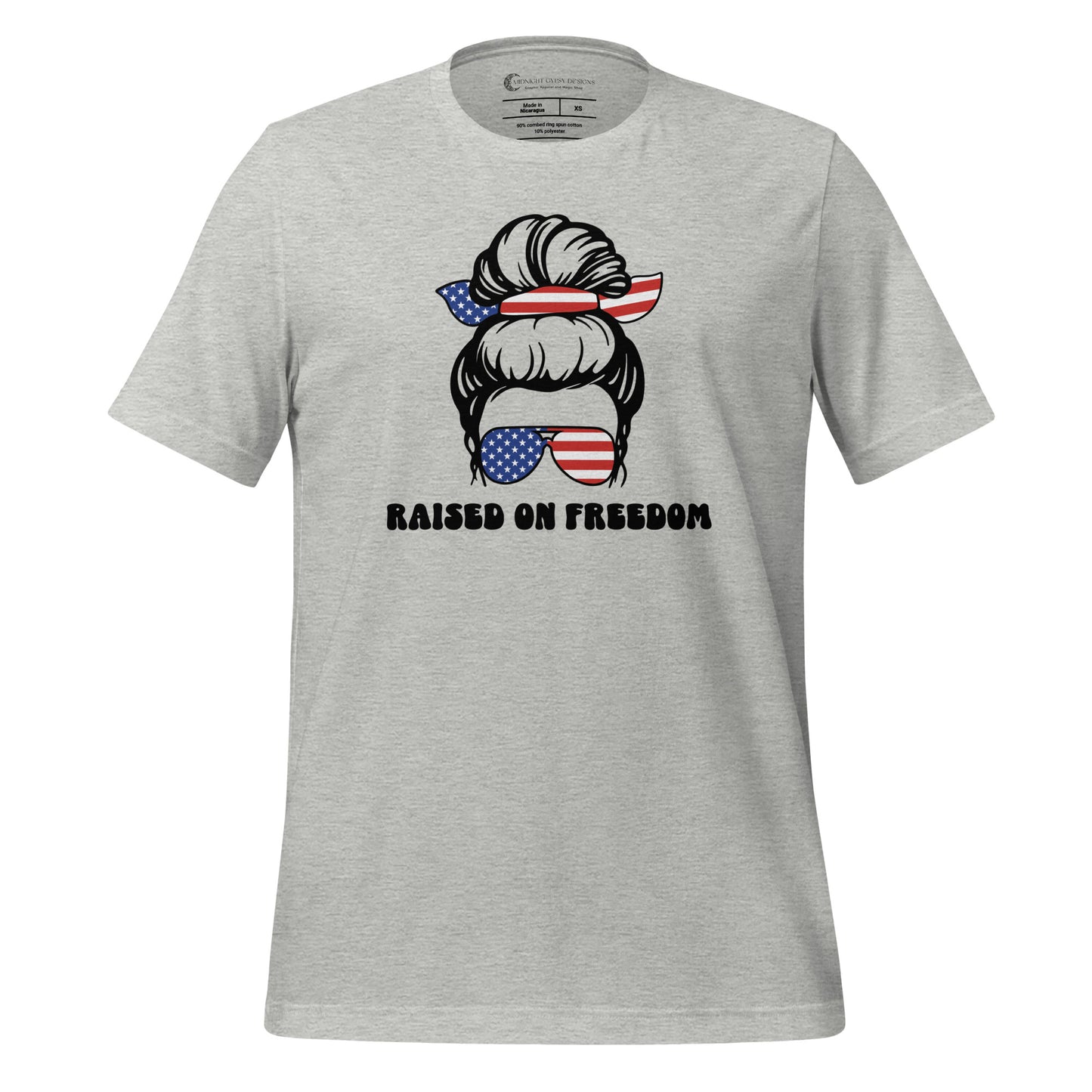 Grey Raised on Freedom shirt with graphic of a woman with an American flag hair tie and sunglasses created by graphic apparel company Midnight Gypsy Designs as part of their patriotic apparel collection. Perfect USA patriotic shirt, All American Girl shirt, girl power shirt, American pride shirt, USA shirt, USA flag shirt, womens patriotic shirt, Fourth of July shirt, Patriotic pride shirt, American flag shirt, Independence Day shirt, & American girl shirt.