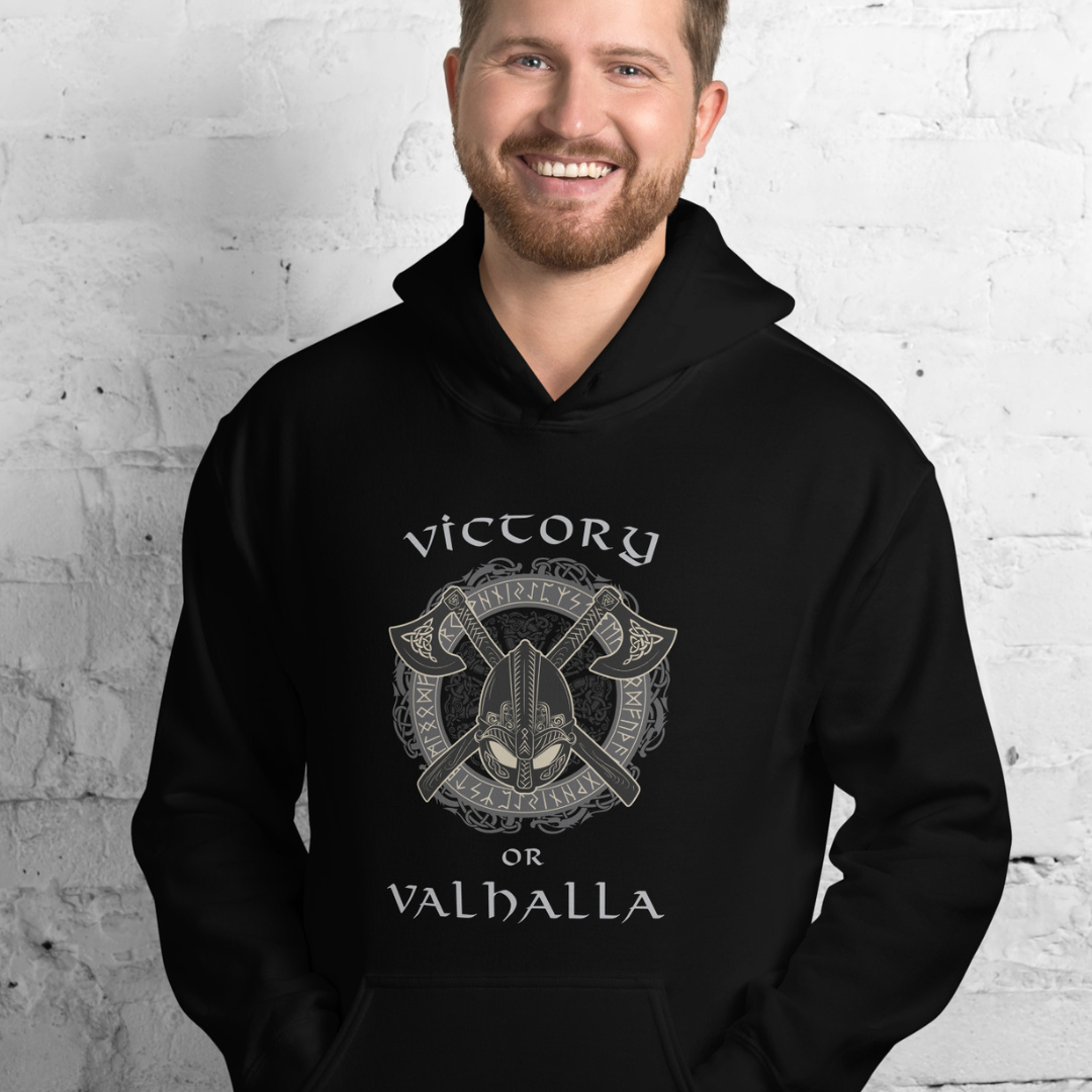 Viking man with a beard wearing a black Victory or Valhalla hoodie with Viking runes and shield with axes created by graphic apparel company Midnight Gypsy Designs as part of their Norse Viking Warrior clothing collection.