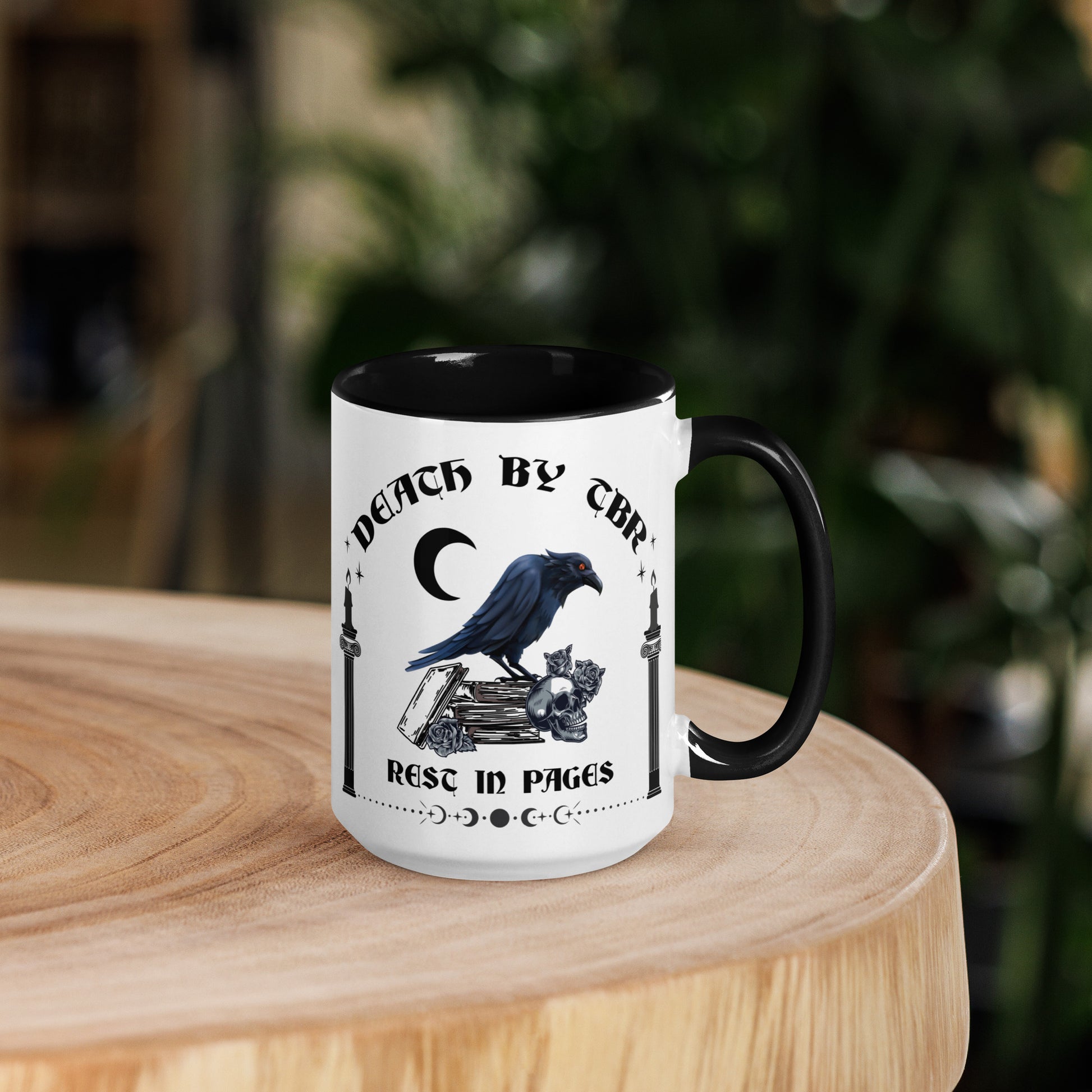 Black and white ceramic mug that reads Death By TBR Rest In Pages with moon, raven standing on a book stack, a skull, and two burning candles from bookish shop Midnight Gypsy Designs.