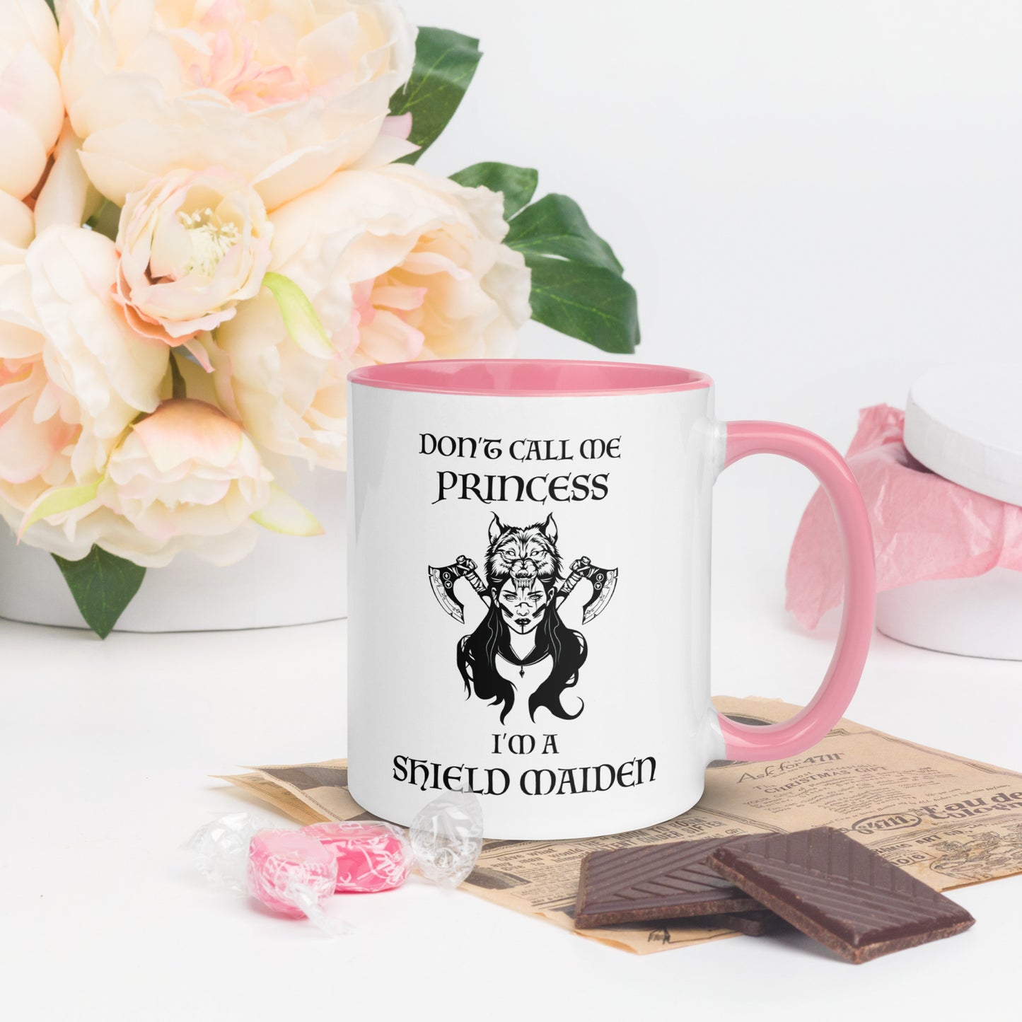 Pink and white ceramic coffee mug with lettering that says Don't Call Me Princess I'm a Shield Maiden with a female Viking Warrior with Norse Viking axes and a wolf created by apparel shop Midnight Gypsy Designs.