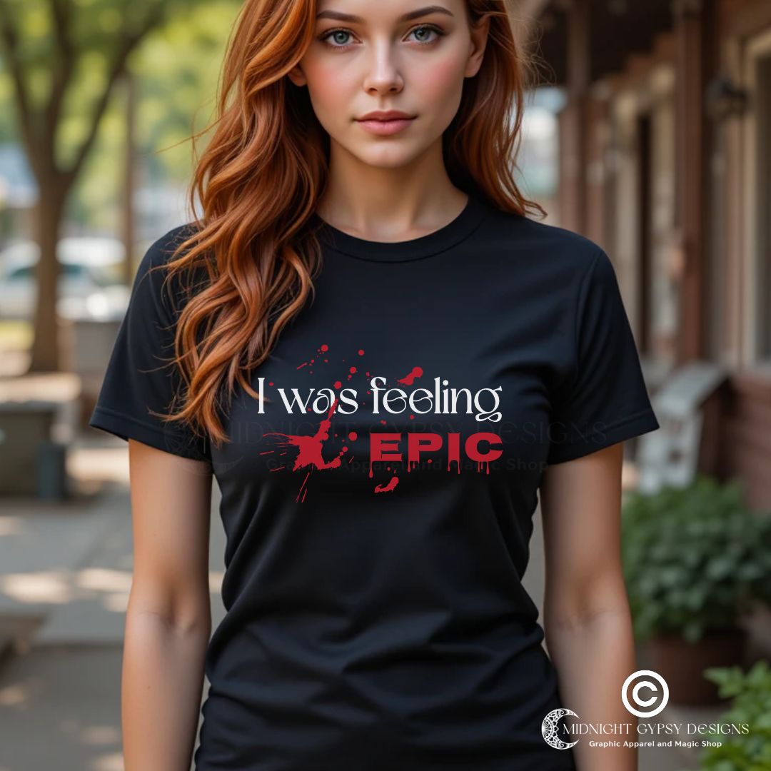 Young woman with long red hair standing in Mystic Falls wearing a black I was feeling Epic shirt with blood splatters inspired by The Vampire Diaries TV show created by fandom graphic apparel company Midnight Gypsy Designs as part of their Vampire Diaries clothing line.