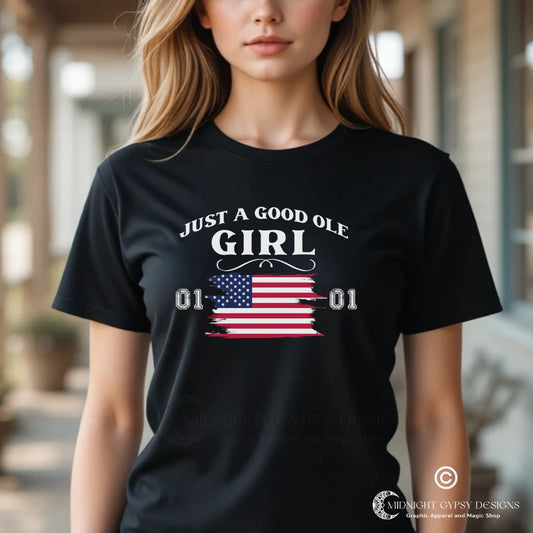 Young woman with long blonde hair standing outside on a southern porch wearing a black Just A Good Ole Girl shirt with American flag  and General Lee 01 number created by fandom graphic apparel company Midnight Gypsy Designs as part of their Patriotic Pride Apparel Collection. Perfect Dukes of Hazard shirt, Dukes of Hazard t-shirt, Daisy Duke shirt, Daisy Duke t-shirt, General Lee shirt, General Lee t-shirt, and  USA Patriotic shirt.