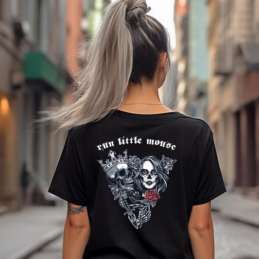 Young woman with blonde hair in a pony tail standing outside on sidewalk with a tattoo on her arm wearing a black t-shirt that reads Run Little Mouse with a skull and day of the dead woman holding a red rose from Haunting Adeline book created by bookish shop Midnight Gypsy Designs.