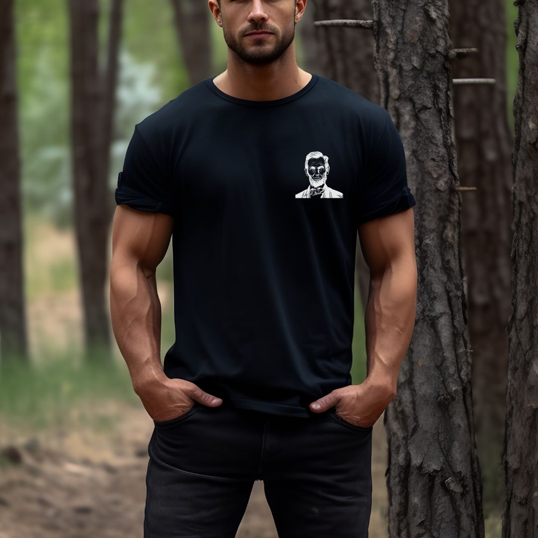 Young man wearing a black patriotic t-shirt that says those who deny freedom to others deserve it not for themselves by Abraham Lincoln with a photo of Abraham Lincoln on pocket of shirt created by apparel shop Midnight Gypsy Designs.