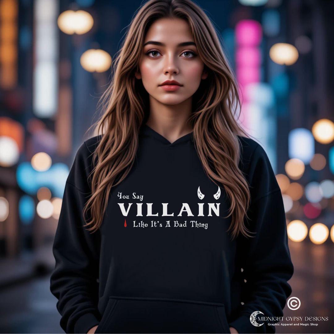 Young woman with long brown hair wearing a black villain hoodie that says You Say Villain Like It's A Bad Thing with devil horns created by graphic apparel company Midnight Gypsy Designs.