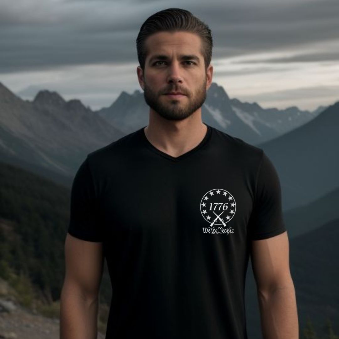 Man with beard standing in front of mountains with short hair wearing a black and white USA patriotic 1776 we the people t-shirt with USA flag and 13 colonial stars created by American patriotic clothing apparel shop Midnight Gypsy Designs.