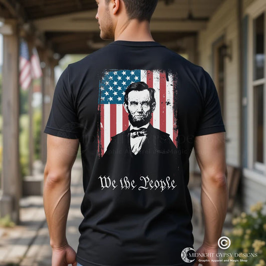 Young muscular man with short hair standing on a southern porch wearing a black We the People shirt with Abraham Lincoln with the USA flag. Perfect Abraham Lincoln shirt or USA military shirt for true patriots created by graphic apparel company Midnight Gypsy Designs.