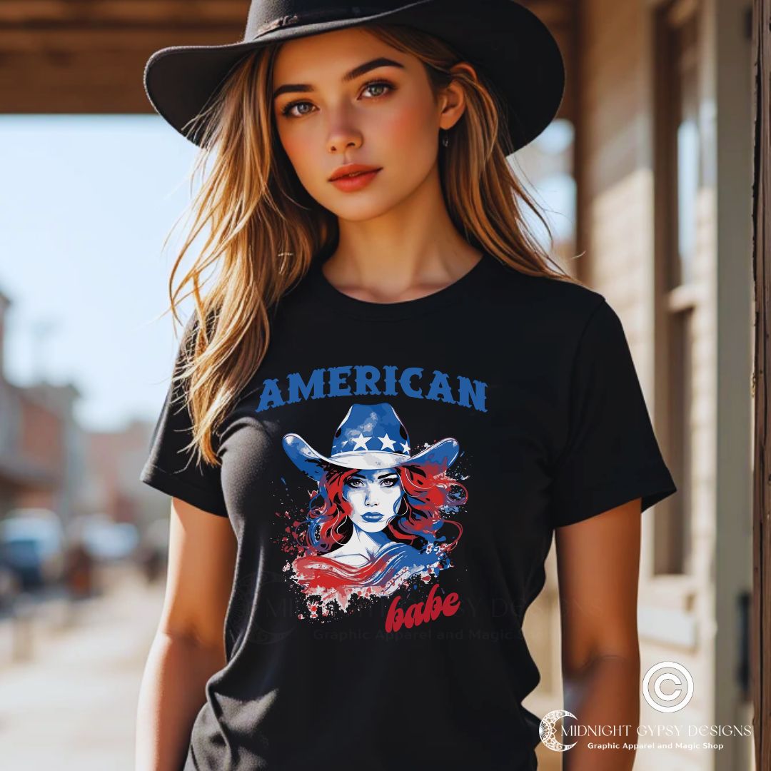 Young woman with long blonde hair in a black cowboy hat wearing a black Western American Babe shirt that has a woman in a blue cowboy hat with white stars. Created by graphic apparel company Midnight Gypsy Designs as part of their patriotic apparel clothing line. Perfect USA patriotic shirt, fourth of July shirt for women, and American pride shirt.