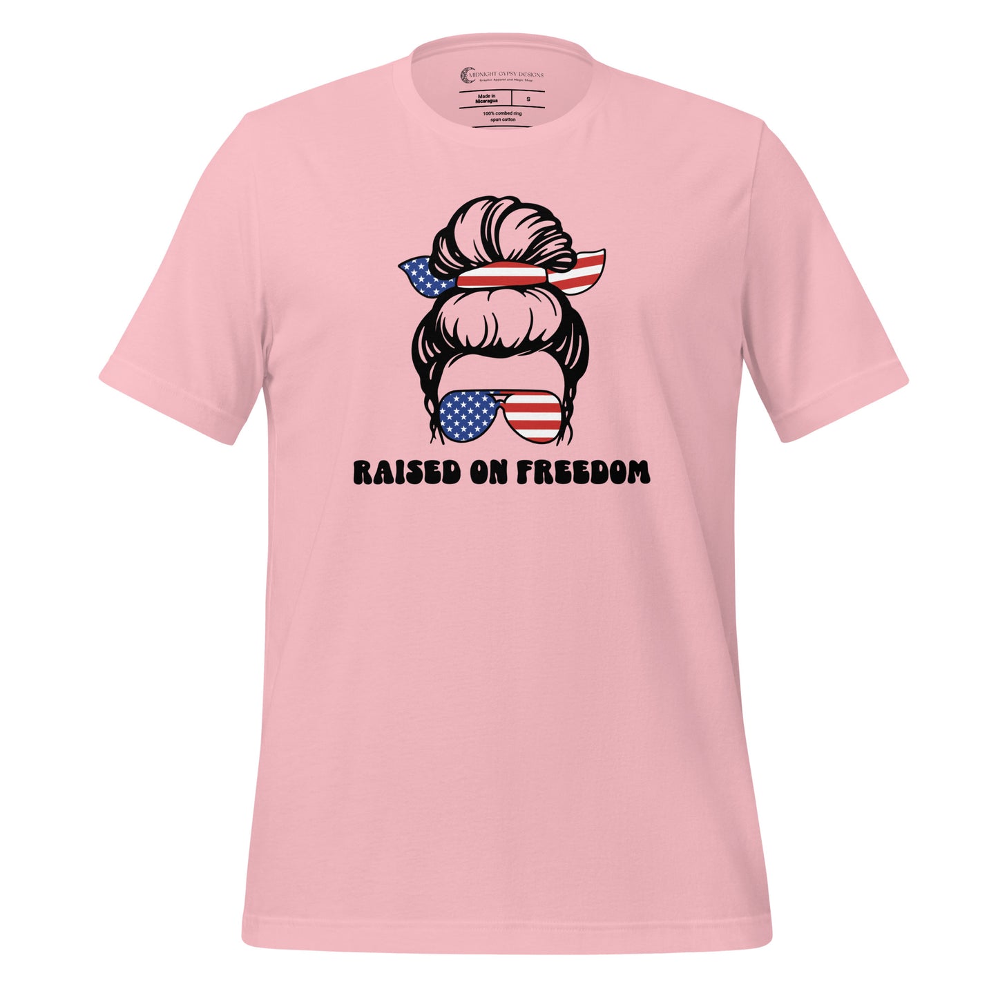 Pink Raised on Freedom shirt with graphic of a woman with an American flag hair tie and sunglasses created by graphic apparel company Midnight Gypsy Designs as part of their patriotic apparel collection. Perfect USA patriotic shirt, All American Girl shirt, girl power shirt, American pride shirt, USA shirt, USA flag shirt, womens patriotic shirt, Fourth of July shirt, Patriotic pride shirt, American flag shirt, Independence Day shirt, & American girl shirt.